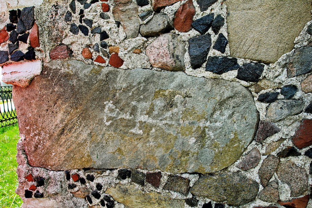 Древний камень с высеченным крестом вмурованный в стену храма